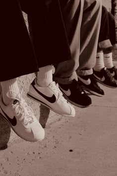 black and white photograph of people's feet with nike shoes on the side walk