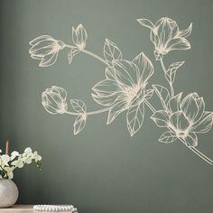 a vase filled with white flowers sitting on top of a table next to a wall