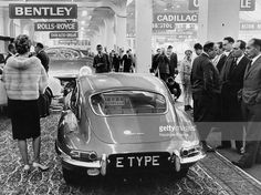 an old photo of people looking at cars in a car showroom