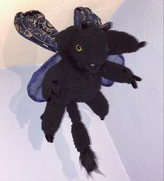 Hand sewn stuffed pooka, inspired by the mythological creature. Color scheme: black fur, yellow eyes, blue wings. Stuffed Animals, Stuffed Animal, Hand Sewn, Hand Sewing, Minnie Mouse, Disney Characters, Disney, Fictional Characters