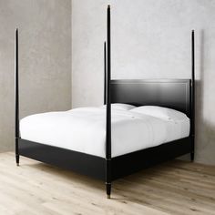 a black bed with white sheets and pillows in a room that has wooden floors, walls and flooring