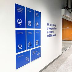 a hallway with blue signs on the wall and wooden doors behind it that say we are a family of people who have to care for a healthier work