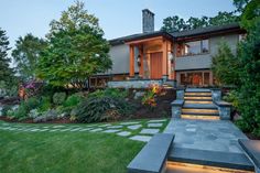 a house with steps leading up to the front door and landscaping around it at dusk