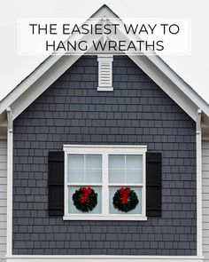 a gray house with two wreaths on the windows and text overlay that reads, the easier way to hang wreaths