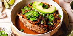 a bowl filled with chili and avocado on top of a table