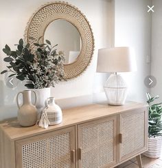 a white vase sitting on top of a wooden dresser next to a mirror and lamp