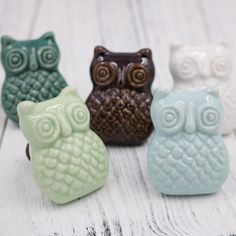 four ceramic owl figurines sitting on top of a white wooden table next to each other