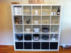 a white bookcase filled with lots of different items on top of a hard wood floor