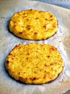 two small pizzas sitting on top of a piece of wax paper covered in grease