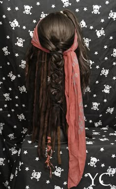 a woman with dreadlocks sitting on top of a black chair next to a skull wallpaper