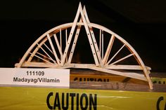 a wooden bridge is on display in a museum exhibit with caution signs below it that read 11 / 11 / 09