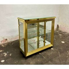 a glass and brass display case on the ground