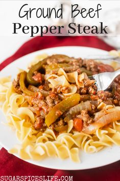 a white plate topped with pasta covered in ground beef and peppers next to a fork