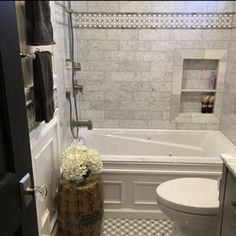 a white toilet sitting next to a bath tub in a bathroom with black and white checkered flooring