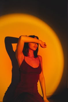 a woman sitting on the floor in front of a yellow circle with her arms behind her head