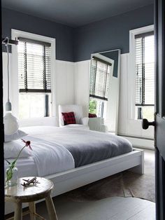 a white bed sitting next to two windows in a bedroom