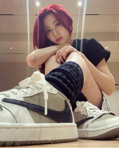 a woman with red hair sitting on top of a white and black sneaker shoe