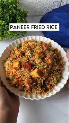 a person holding a plate of food with rice and tofu on it next to some parsley