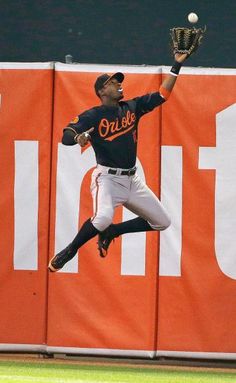 a baseball player catching a ball in mid air with his glove out and the ball coming toward him