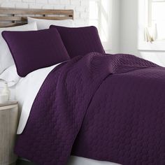 a bed with purple bedspread and pillows