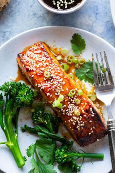 a white plate topped with salmon and broccoli