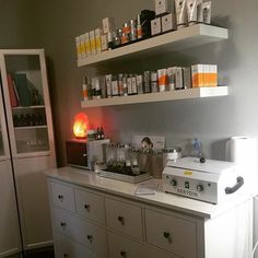 a white counter top sitting next to a shelf filled with bottles and other items on it