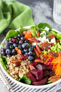 a white bowl filled with different types of vegetables and nuts on top of a table