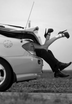 a woman sitting on the back of a car with her feet up in the air