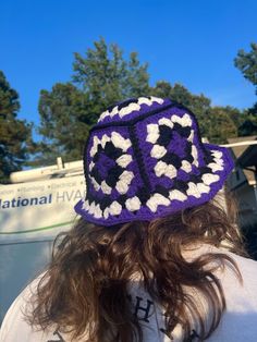 a woman wearing a purple and white crocheted hat on top of her head