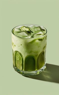 a glass filled with green liquid on top of a table