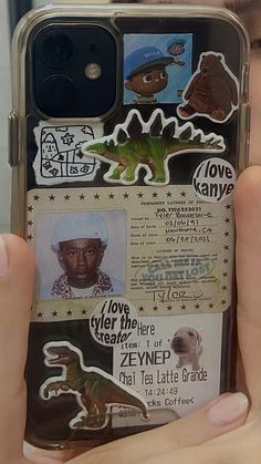 a person holding up a cell phone case with stickers on the back of it