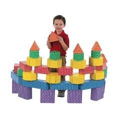 a young boy standing in front of a pile of blocks