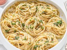 a white dish filled with pasta and garnished with parmesan sprinkles