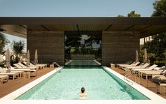 a woman in a swimming pool surrounded by lounge chairs