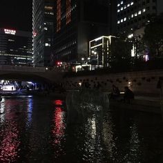 a boat traveling down a river in the middle of a city at night with lights on