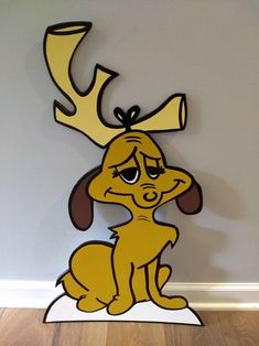 a cartoon dog sitting on top of a wooden floor next to a wall with a deer's antlers on it