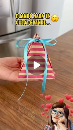 a person holding up a small gift in front of a refrigerator with hearts on it