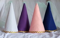 four different colored cones sitting on top of a white sheet covered table next to each other