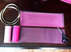 two rolls of pink fabric and scissors on a table with purple material next to them