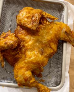 a fried chicken sitting on top of a metal pan