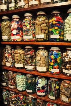 many jars filled with candy and candies are on the shelves in a store,