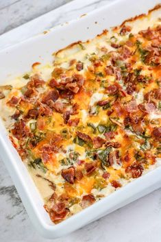 a casserole dish with bacon, cheese and broccoli in it on a marble surface