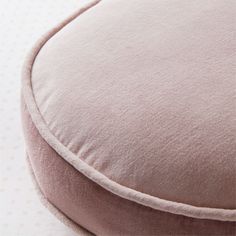 a close up of a pink cushion on a white bed with polka dot print wallpaper