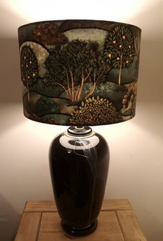 a table lamp with a black vase underneath it