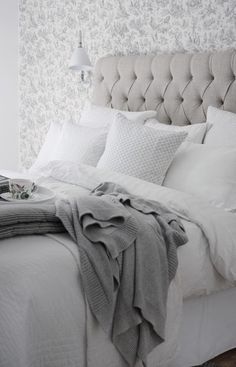 a bed with white sheets and pillows in a bedroom