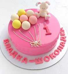 a pink birthday cake with balloons and a teddy bear