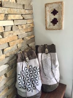 two bags sitting next to each other on a wooden table in front of a stone wall