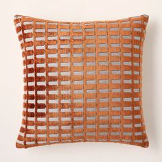 an orange and grey decorative pillow sitting on top of a white wall