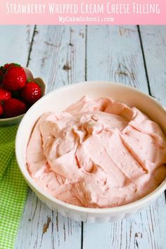 strawberry whipped cream cheese filling in a bowl next to strawberries on a green and white checkered napkin