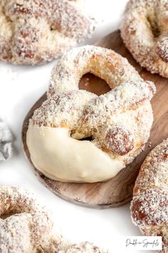 powdered sugar covered donuts sitting on top of a wooden board next to other doughnuts